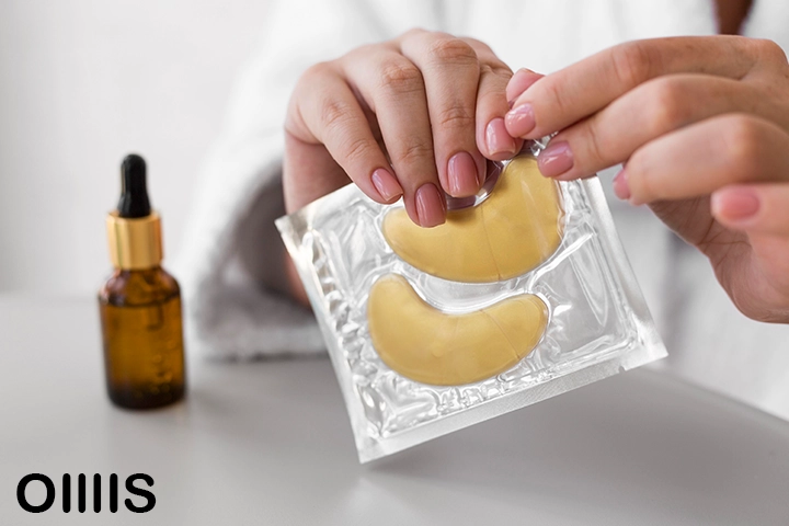 a bag of eye patches is opening in front of camera with a bottle of essential oil beside it