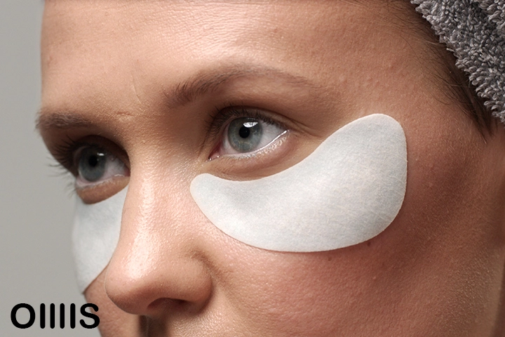 a close up picture of a lady using white eye patches on her face