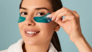 a woman using branded eye patches with blue color on her face