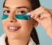 a woman using branded eye patches with blue color on her face